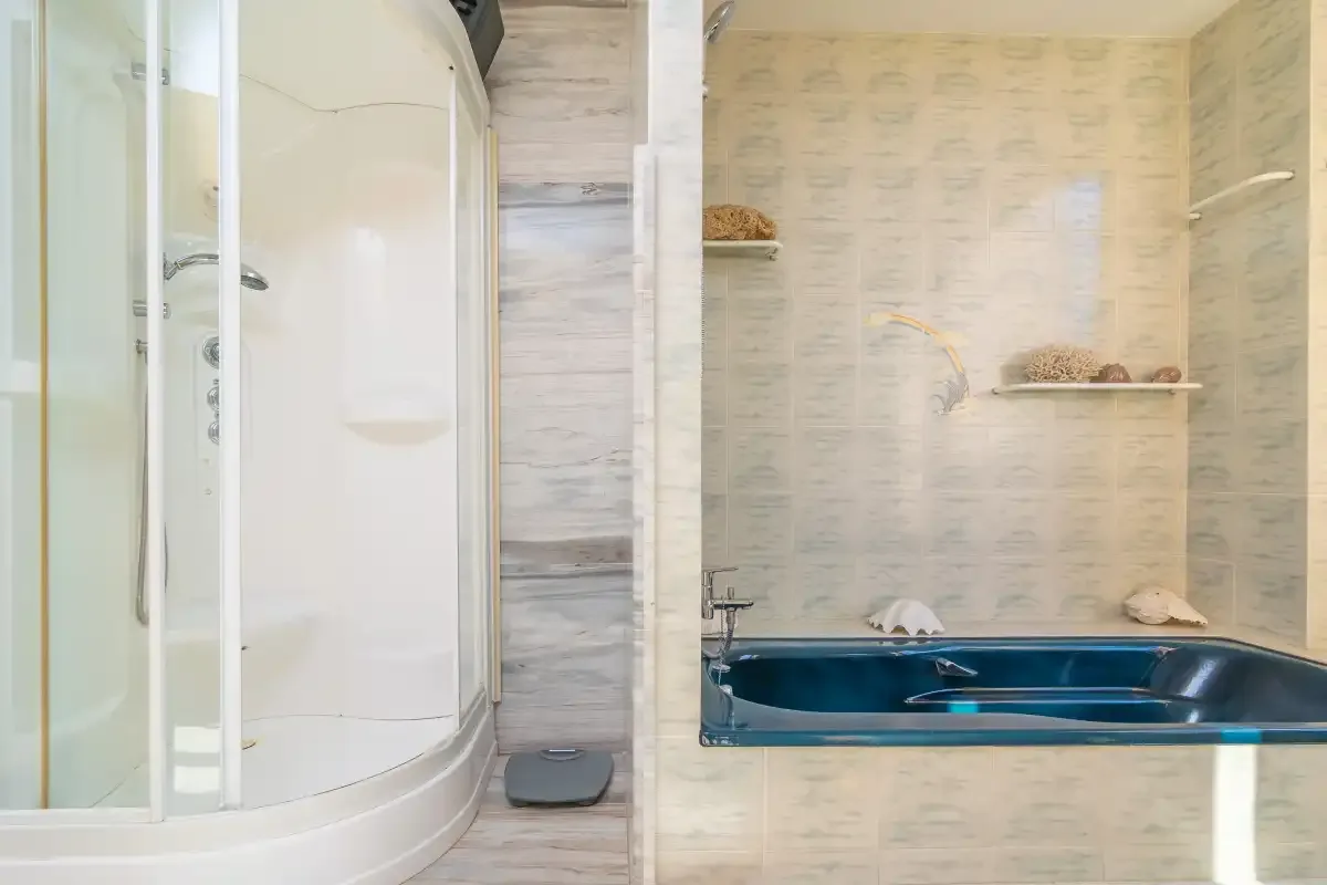 A tiled bathroom with a curved shower enclosure and a built-in tub.