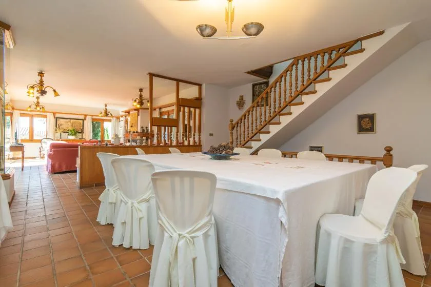 A dining area with a long table set with a white tablecloth and chairs.