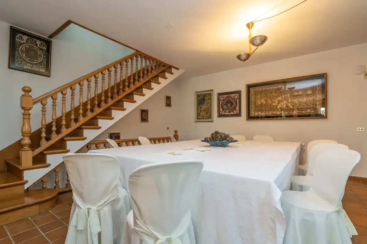 A dining area with a table set beneath a wooden staircase.