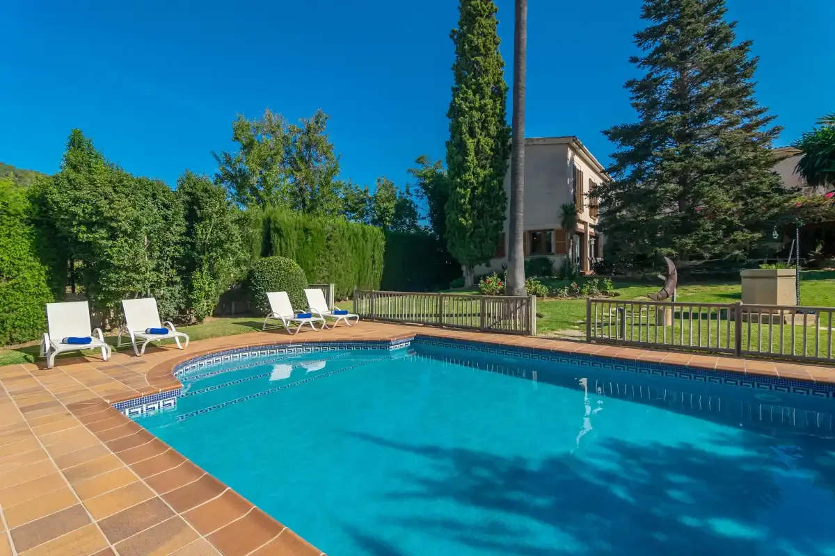 An outdoor swimming pool beside a tiled deck and garden.