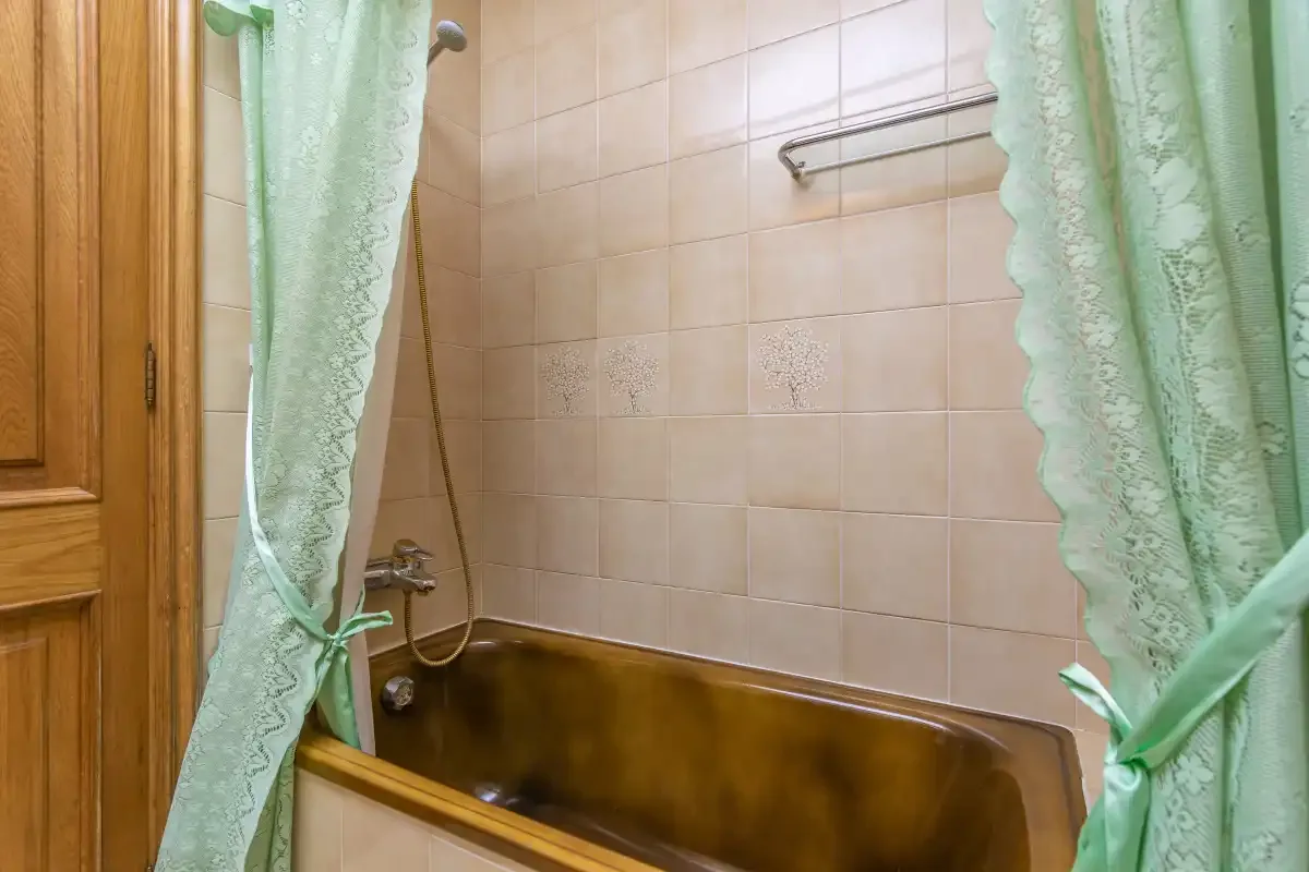 A bathroom with a bathtub behind green curtains.