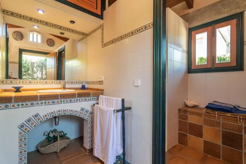 A tiled bathroom with a sink, mirror, and window.