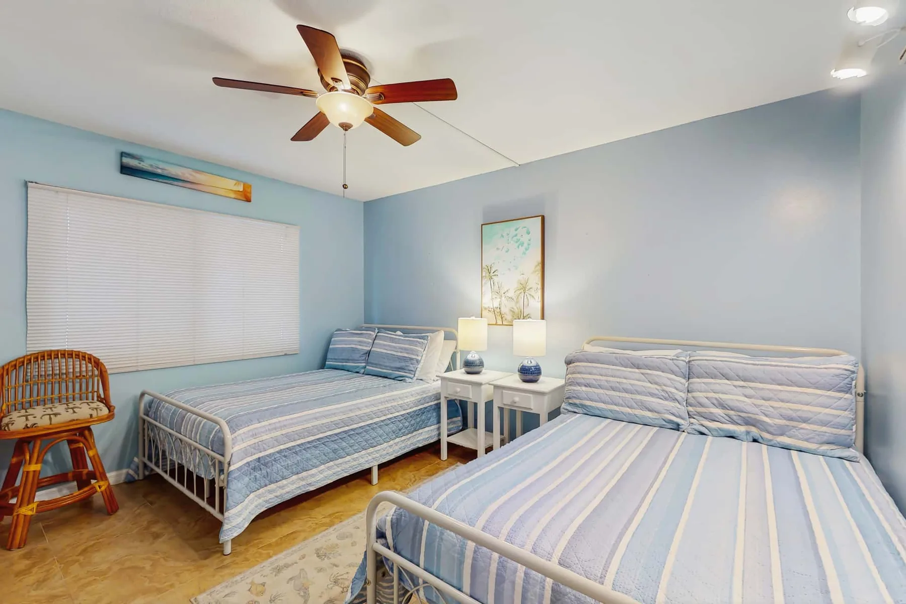 A bedroom with two beds, a small table, and a ceiling fan.