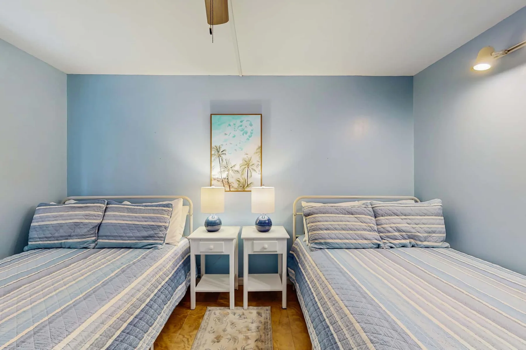 A bedroom with two beds and matching bedside tables.
