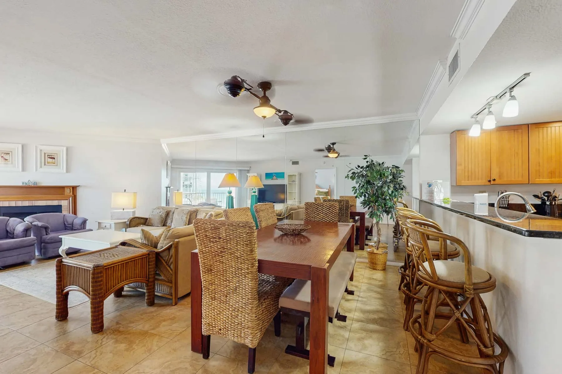 An open-plan living and dining area with a long wooden table and wicker seating.