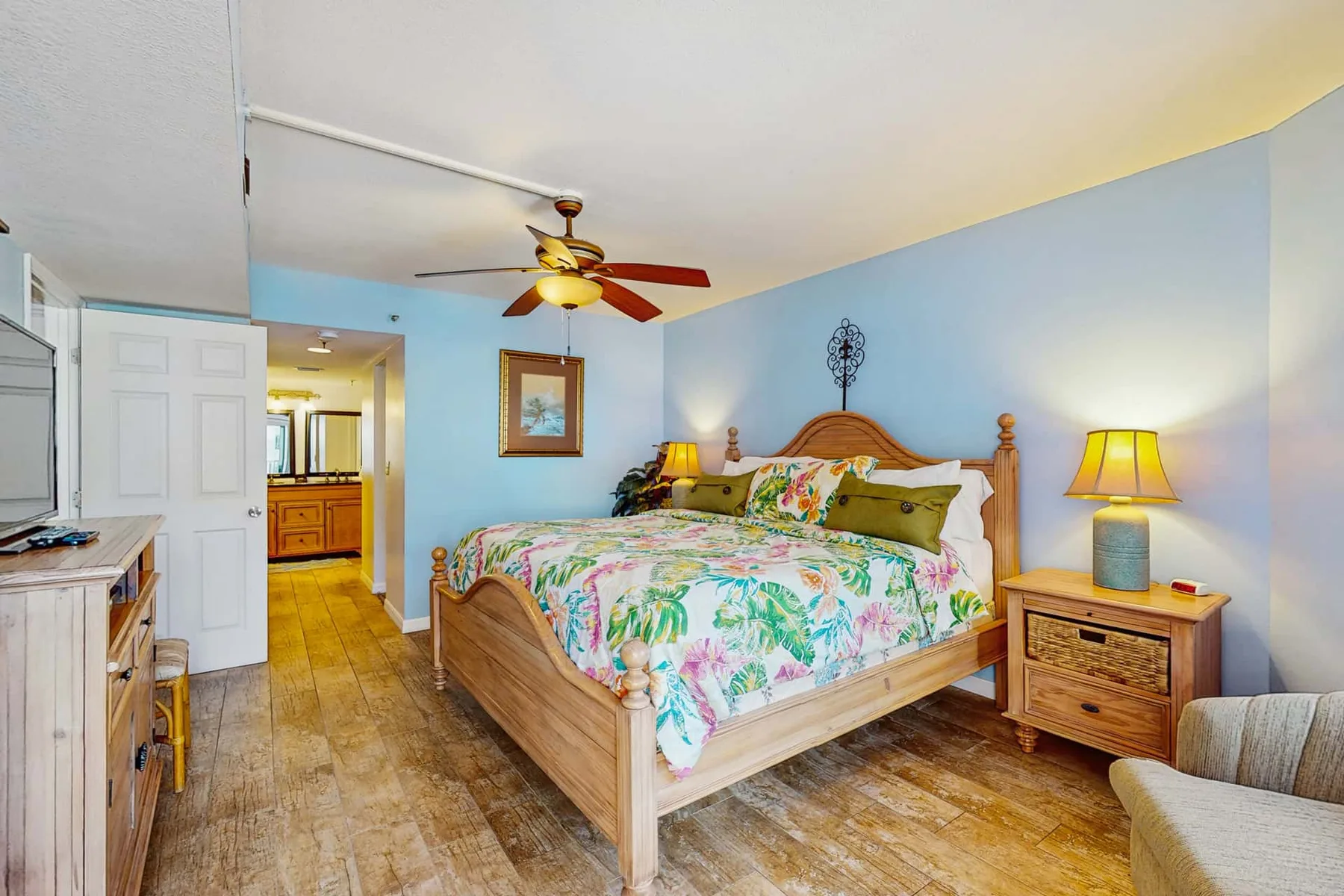 A bedroom with a wooden bed, floral bedding, and bedside lamps.