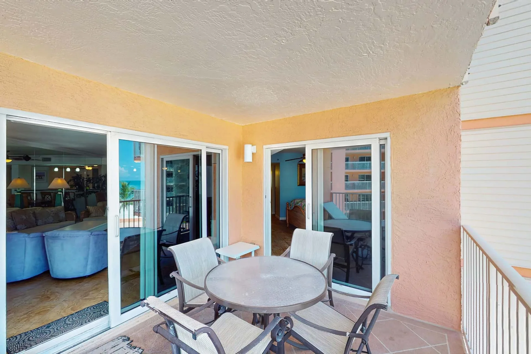 A covered balcony with outdoor seating and sliding glass doors.