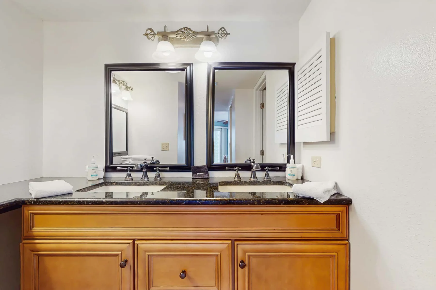 A bathroom vanity with two sinks sits beneath a pair of mirrors.