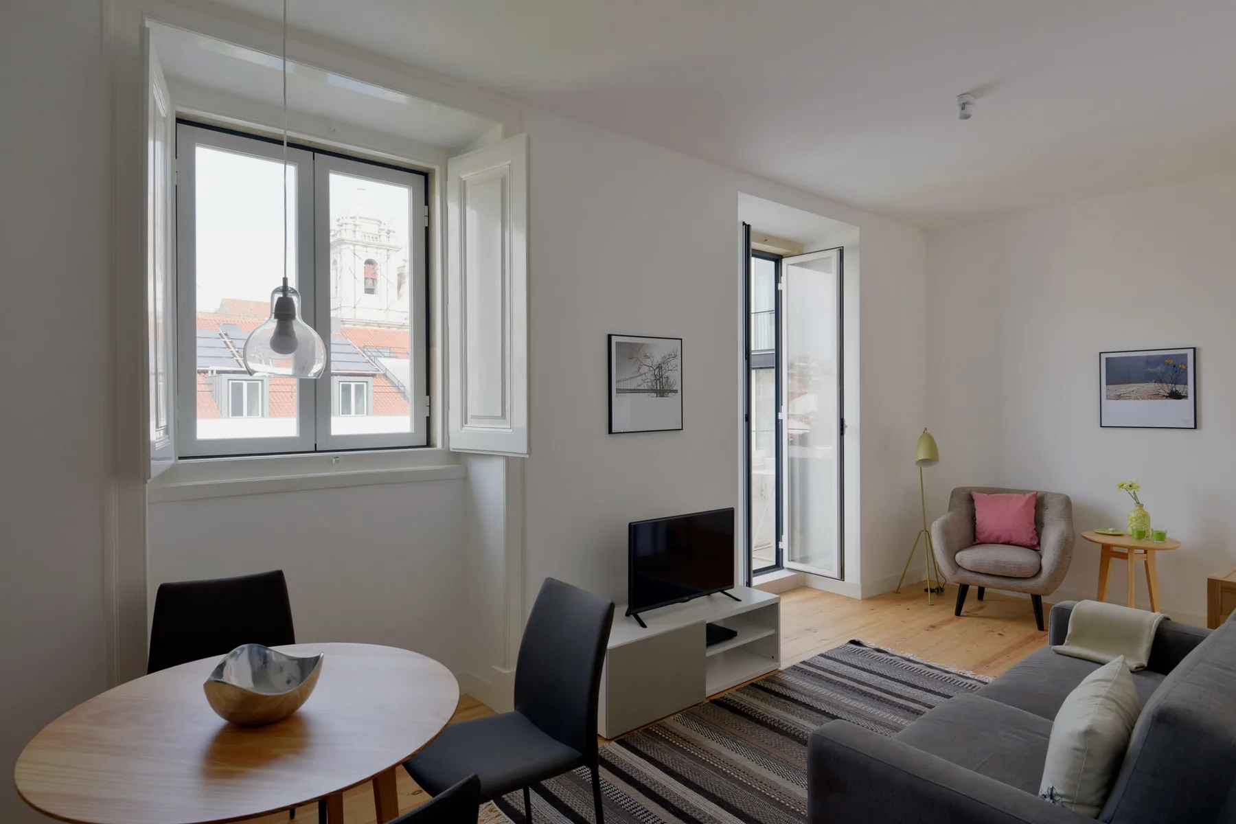 A bright living room with a dining table, seating, and windows.