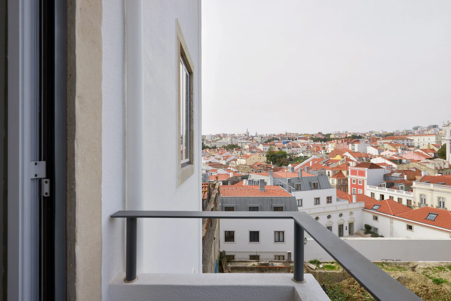 A small balcony overlooks a cityscape of red-tiled rooftops.
