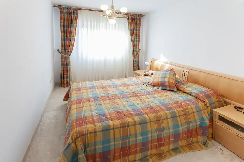 Dormitorio con una cama doble cubierta con ropa de cama a cuadros de colores.