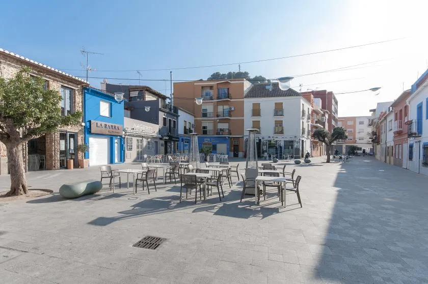 Una plaza pavimentada con mesas y sillas al aire libre entre los edificios.