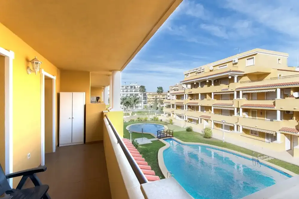 Un balcón da a una piscina y a jardines entre edificios de apartamentos.