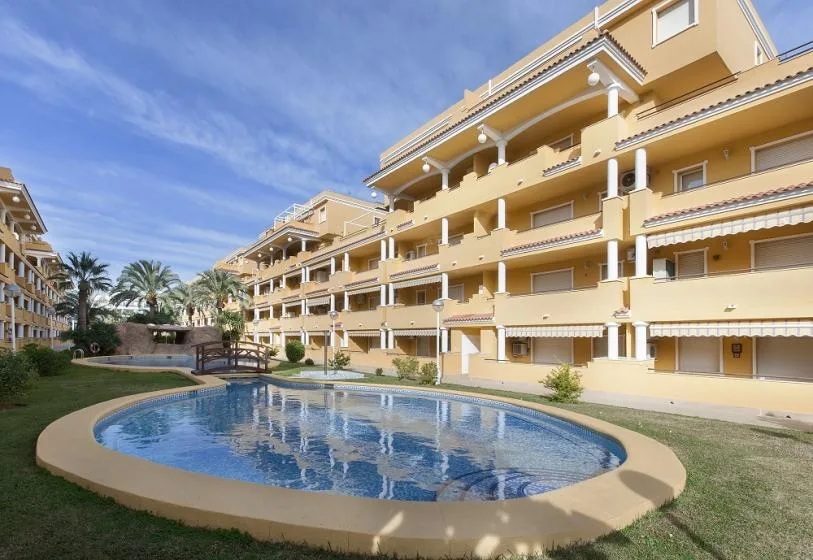An outdoor swimming pool sits beside a multi-story apartment building.