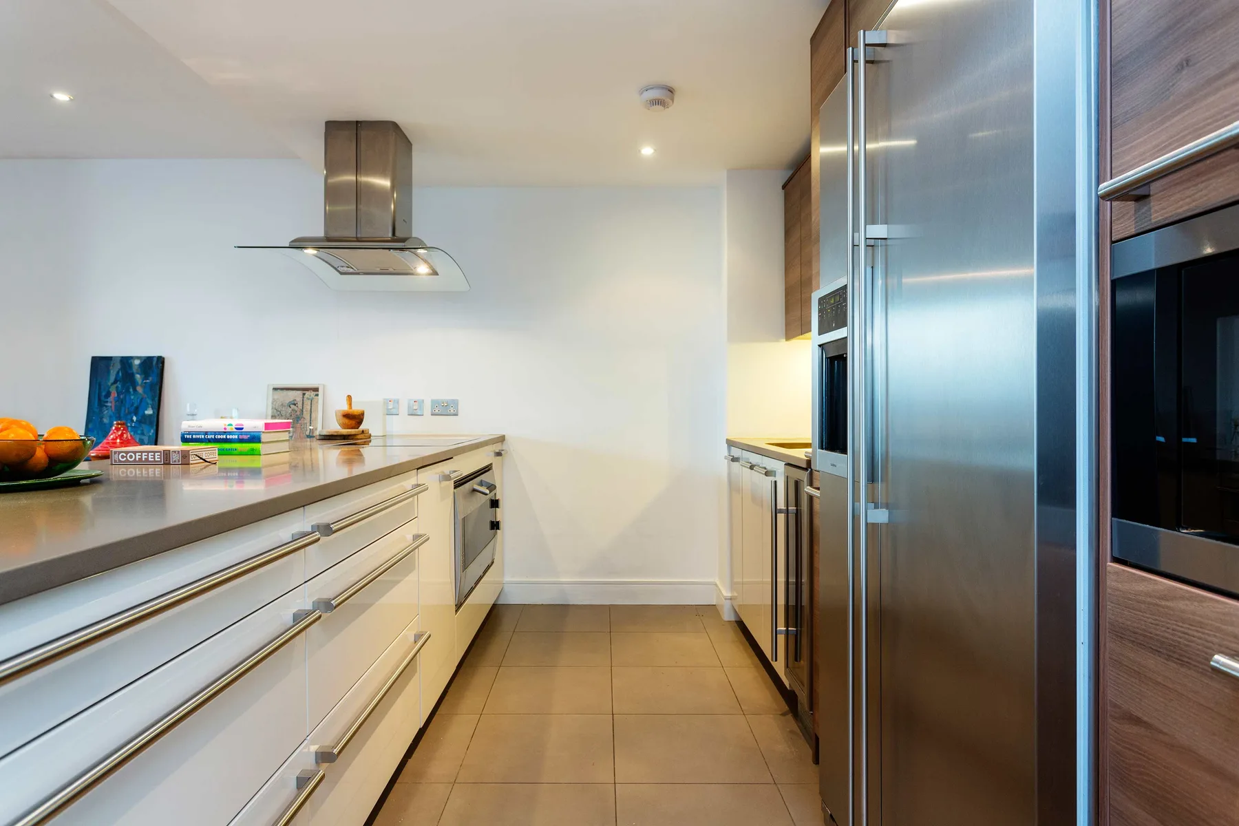 Una cocina moderna con encimeras largas, gabinetes y electrodomésticos de acero inoxidable.