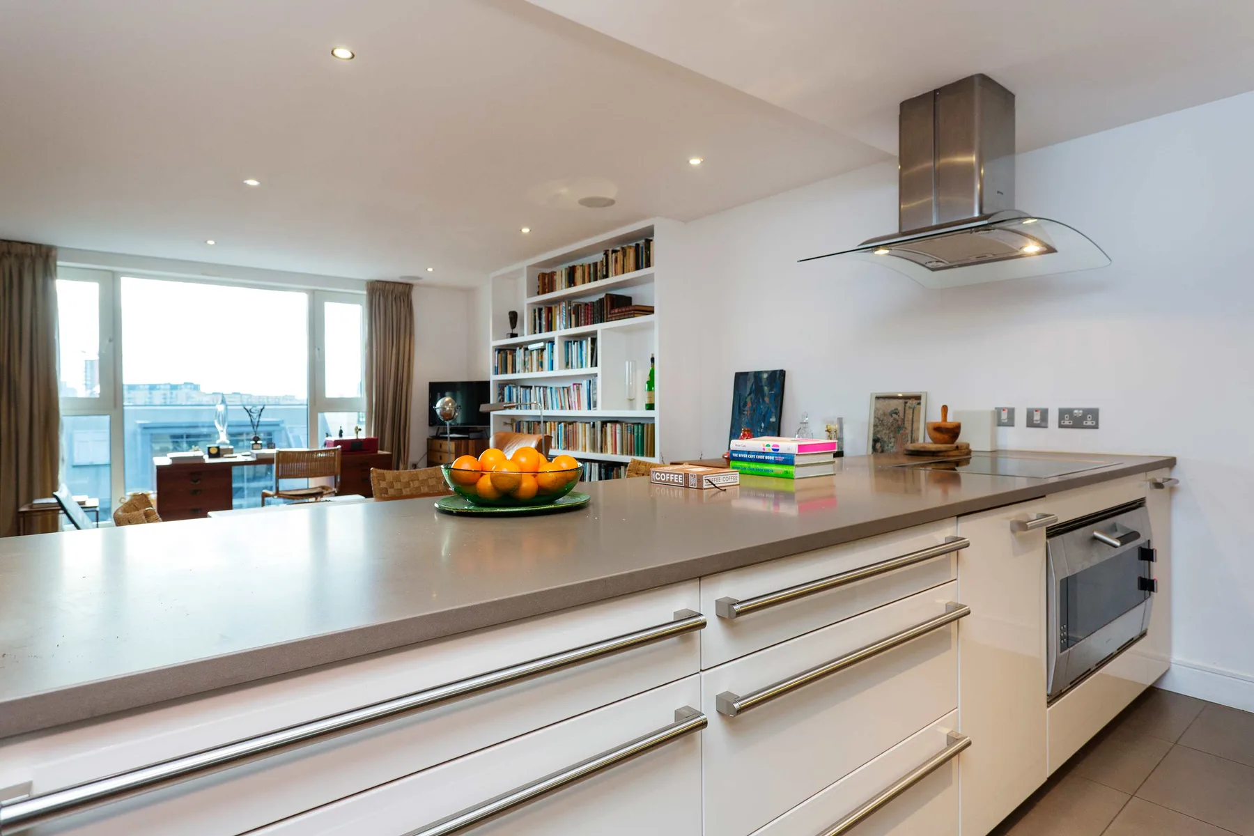 Una cocina luminosa con una isla larga, una placa de cocina y grandes ventanas.