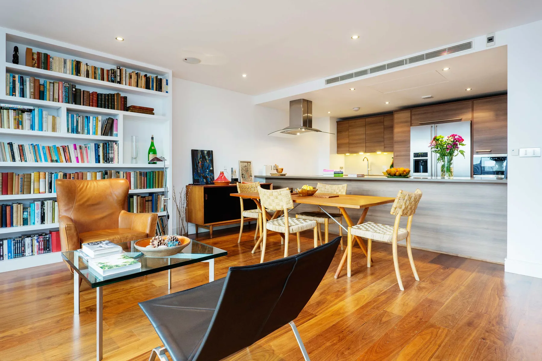 Una luminosa sala-comedor de concepto abierto con cocina y estanterías empotradas.