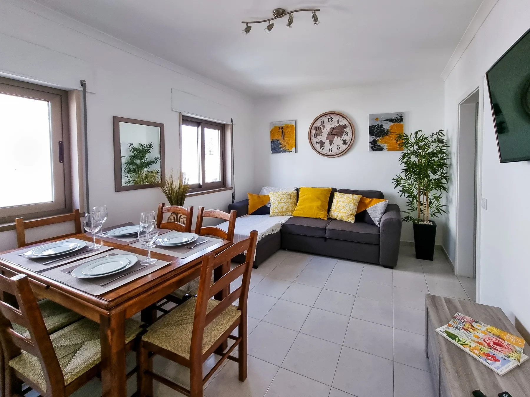 Sala de estar y comedor con una mesa de madera y un sofá oscuro.