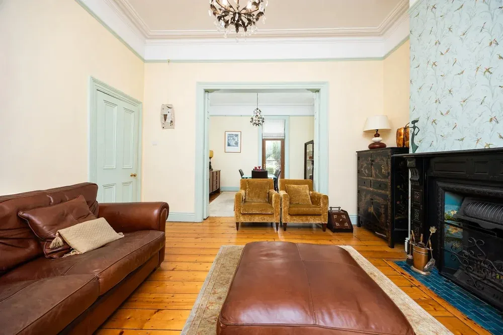 A living room with brown leather seating and a fireplace.