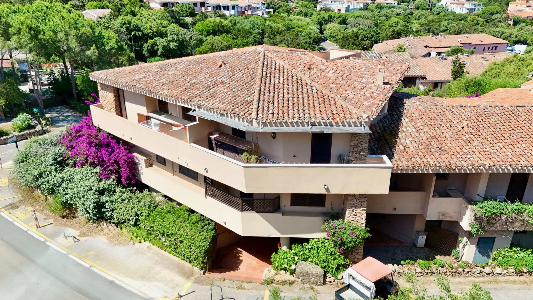 Aerial view of a low-rise building with a tiled roof and surrounding greenery.