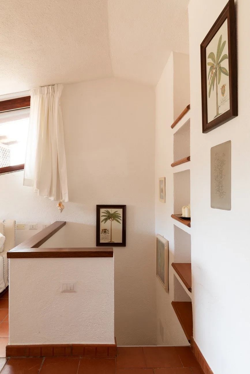A bright interior landing with framed botanical artwork and a short half wall.