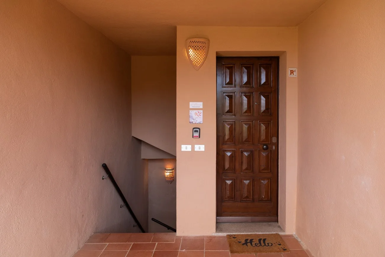 A warm-toned entryway with a dark wooden door and tiled floor.