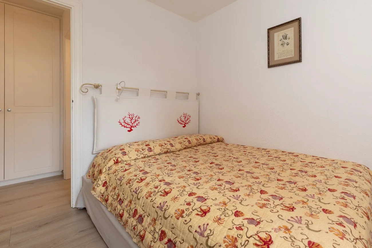 A bedroom with a bed covered in a floral-patterned bedspread.