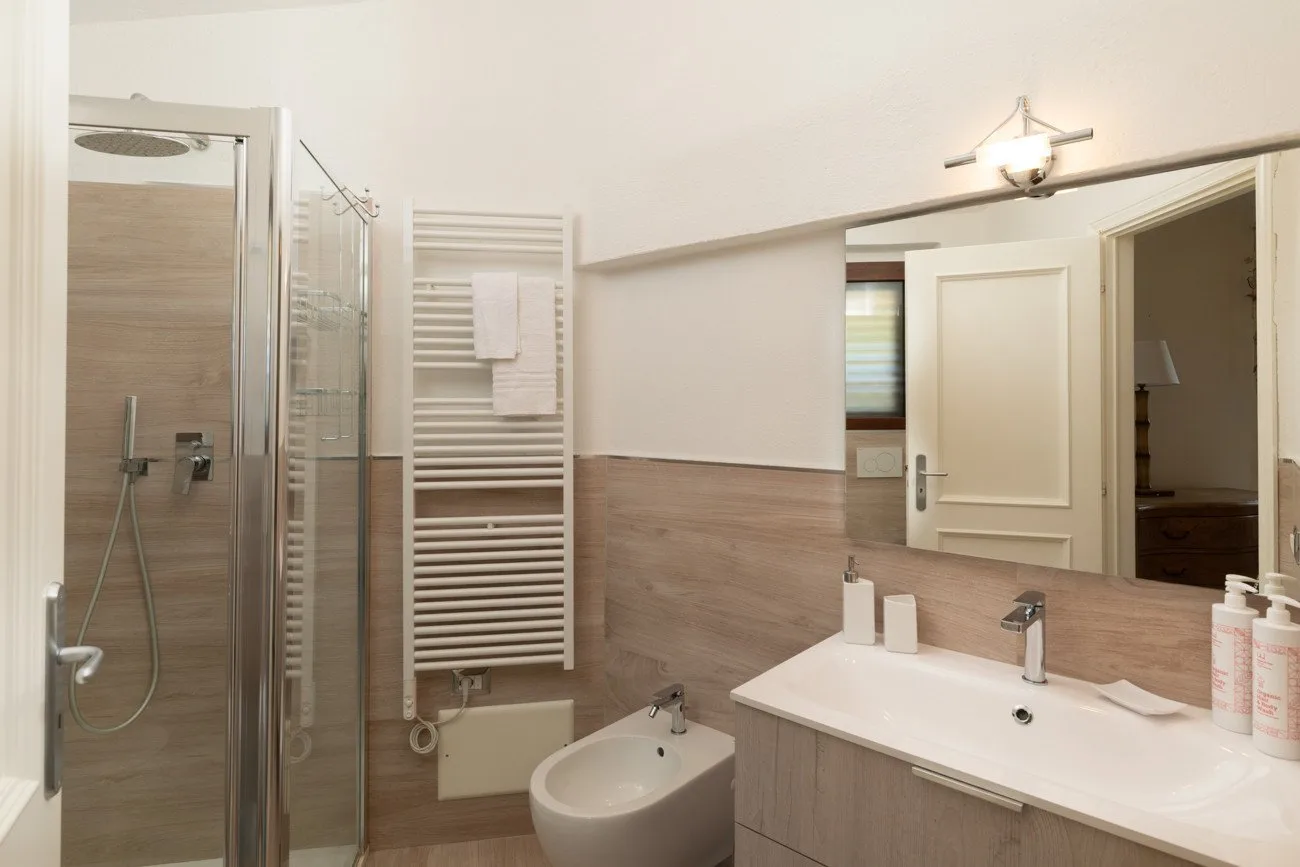 A bathroom with a glass shower, sink, and bidet.
