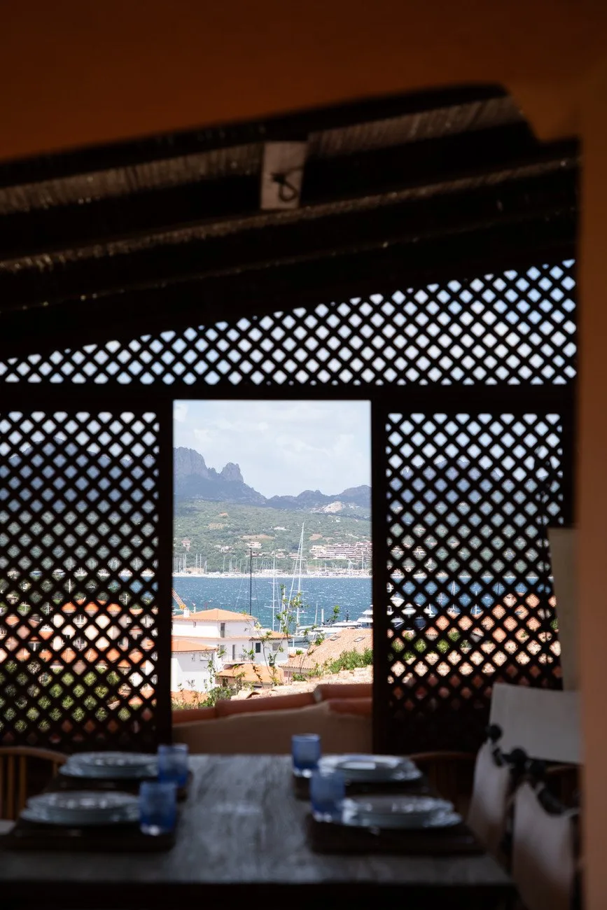 A dining area with a view of the waterfront through a lattice screen.