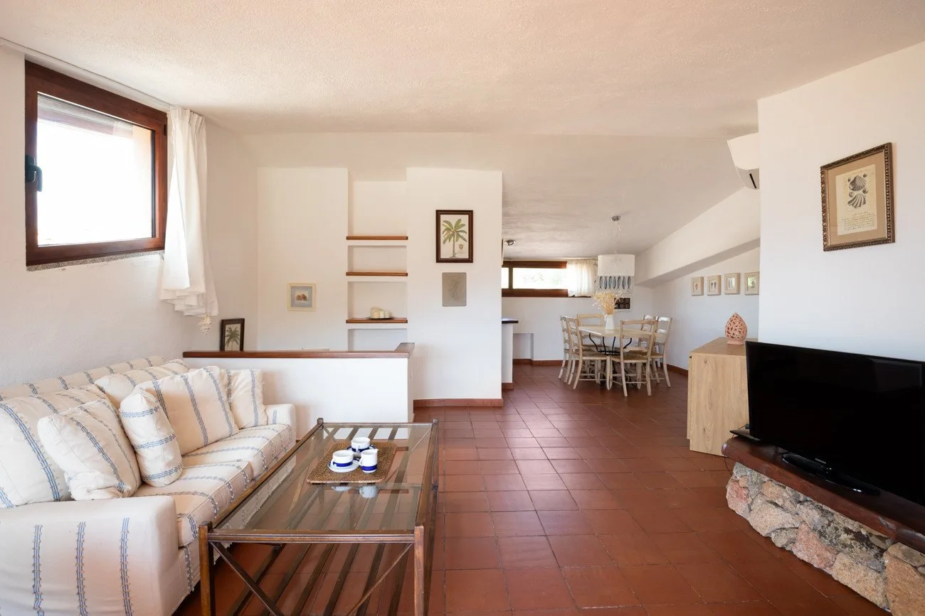 A bright living and dining area with a striped sofa and a dining table.