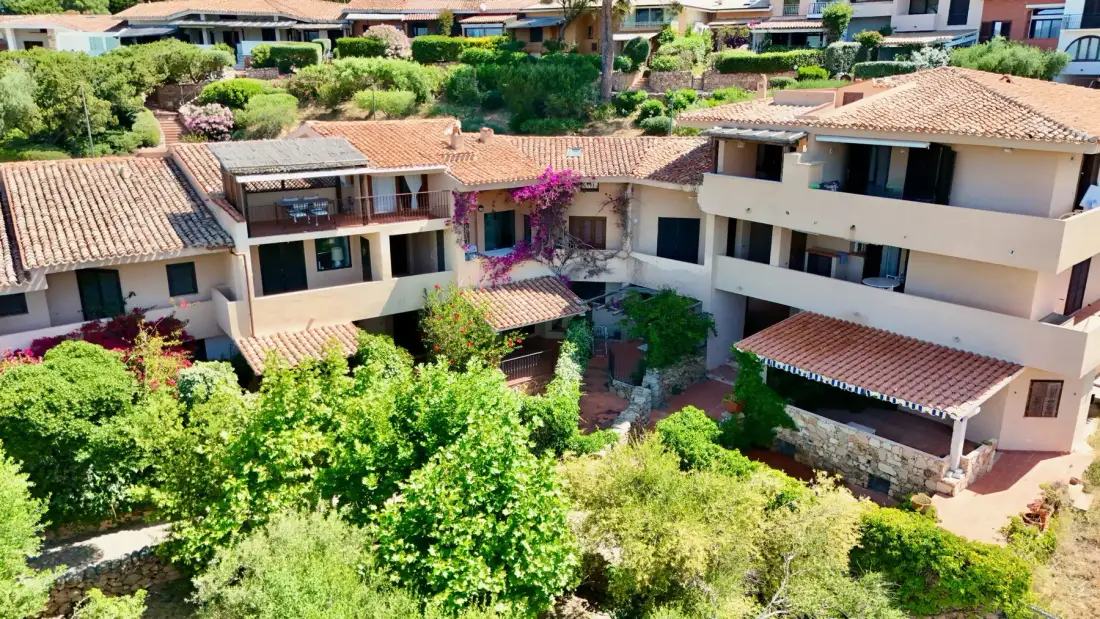 Aerial view of a cluster of buildings with tiled roofs and surrounding greenery.