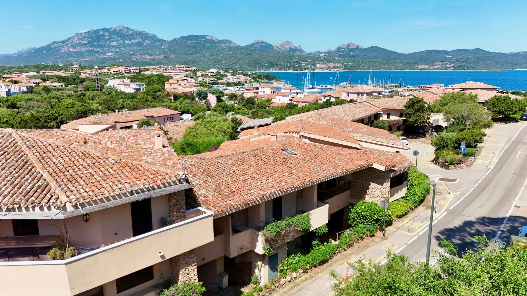 Aerial view of tiled-roof buildings beside a coastal town and blue harbor.