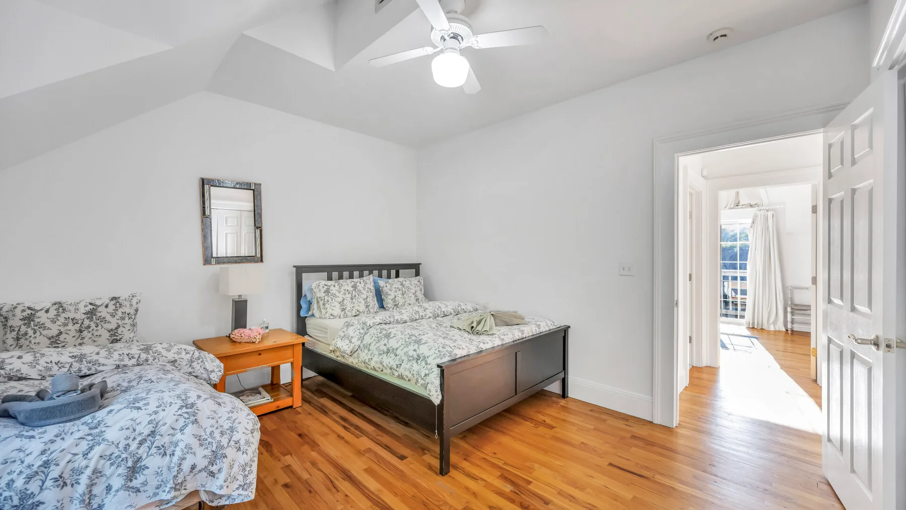 Un dormitorio con una cama, una mesita auxiliar y un ventilador de techo.