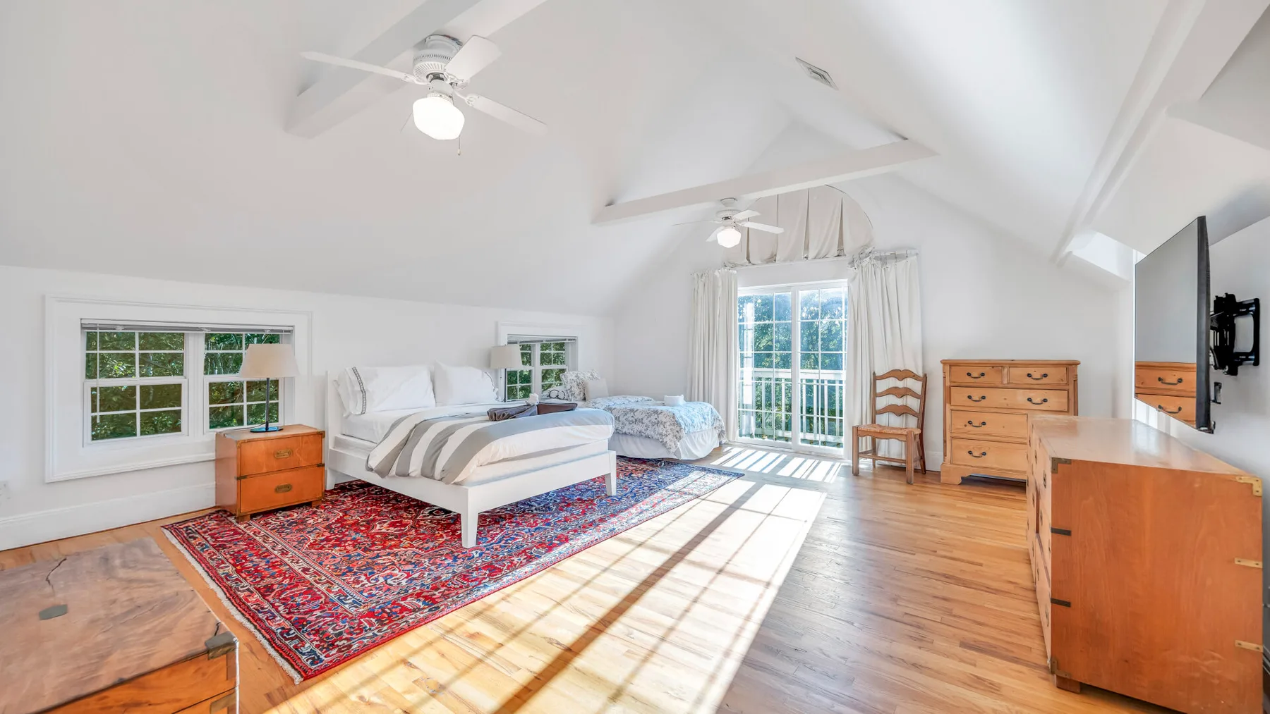 Un dormitorio luminoso tiene una cama, muebles de madera y luz del sol sobre el suelo.