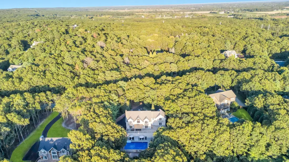 Vista aérea de una casa rodeada por una extensa zona arbolada.