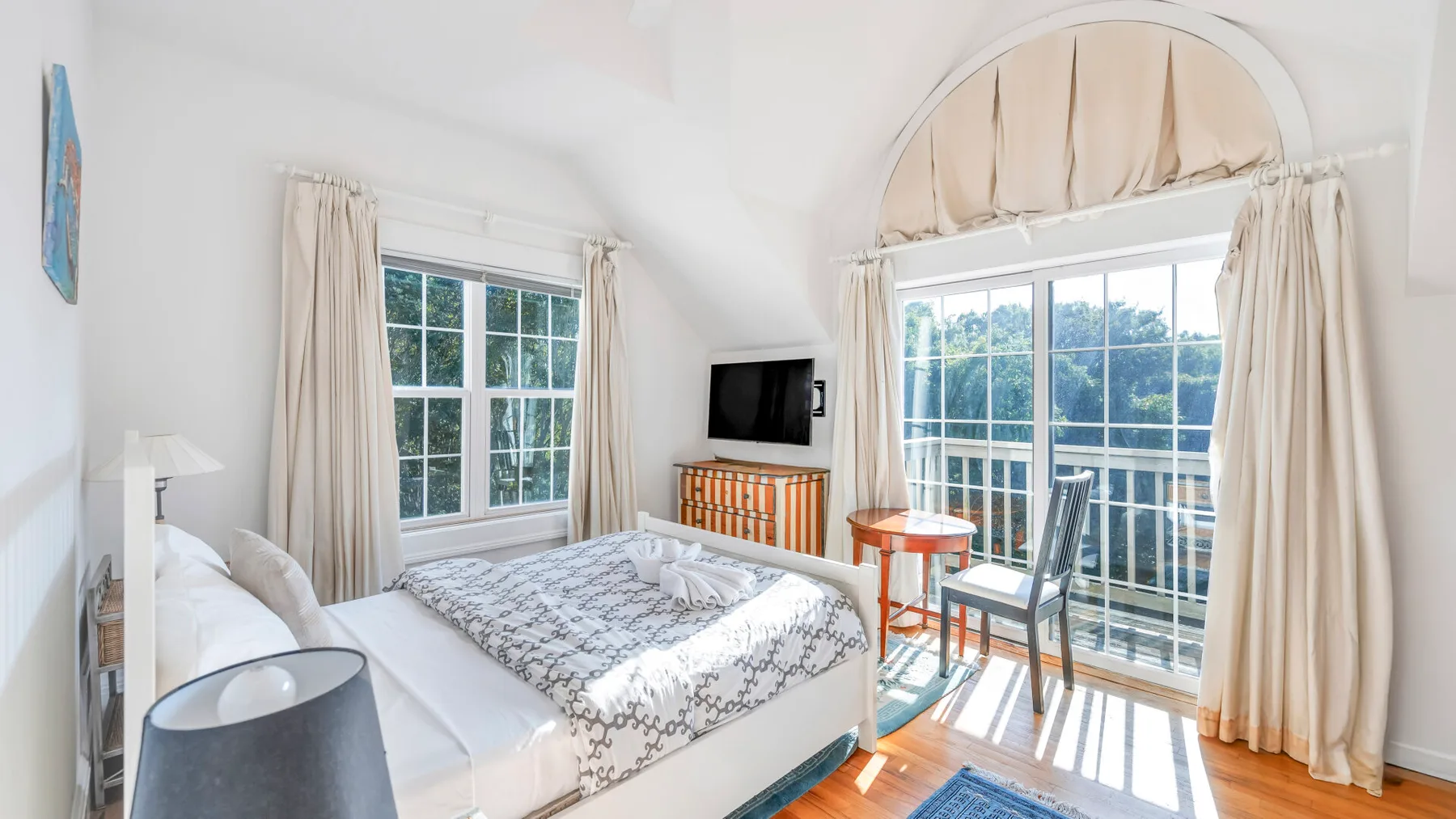 Un dormitorio luminoso con una cama y grandes ventanas con vistas a la vegetación.