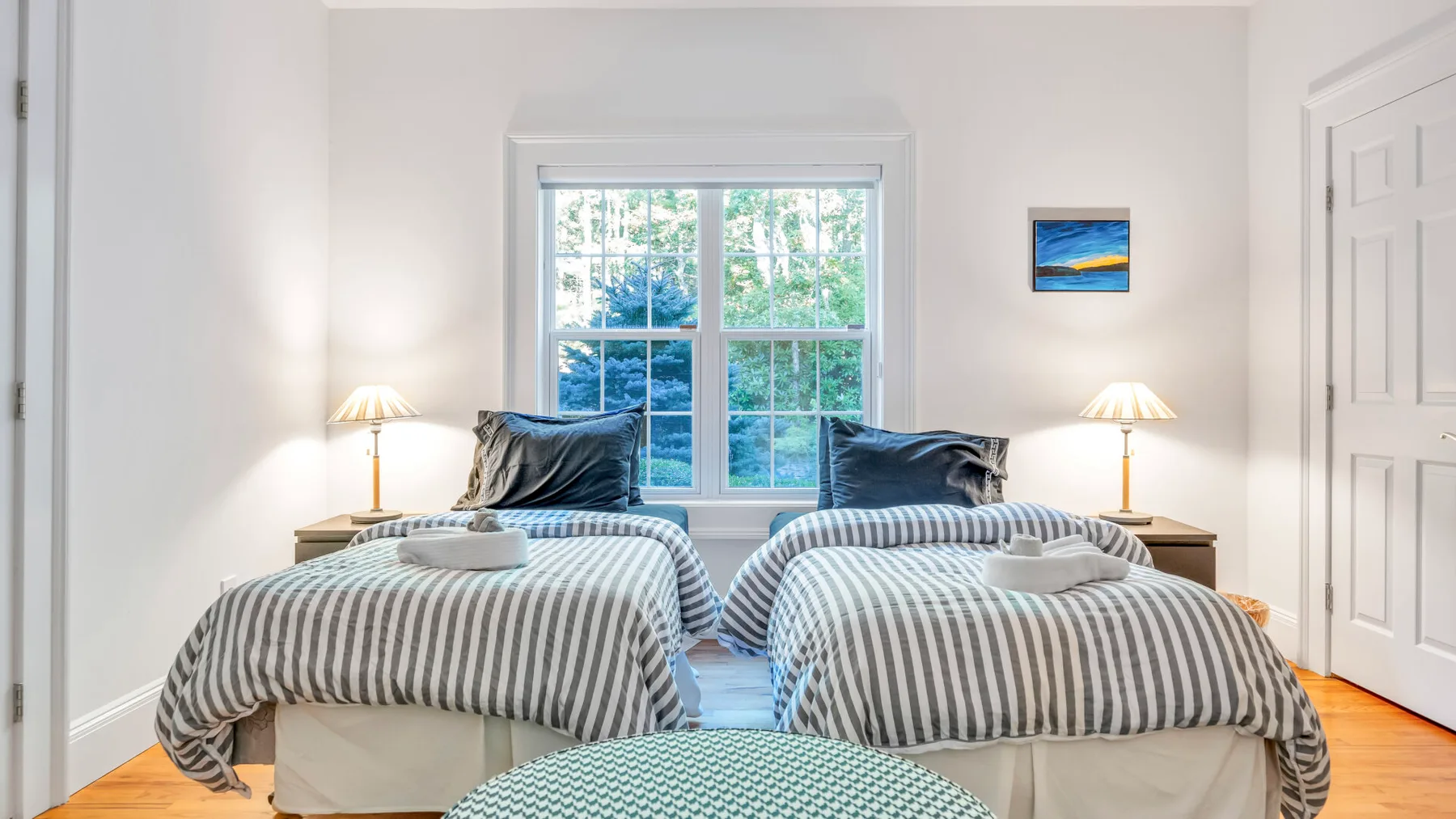 Un dormitorio luminoso con dos camas junto a una ventana grande.
