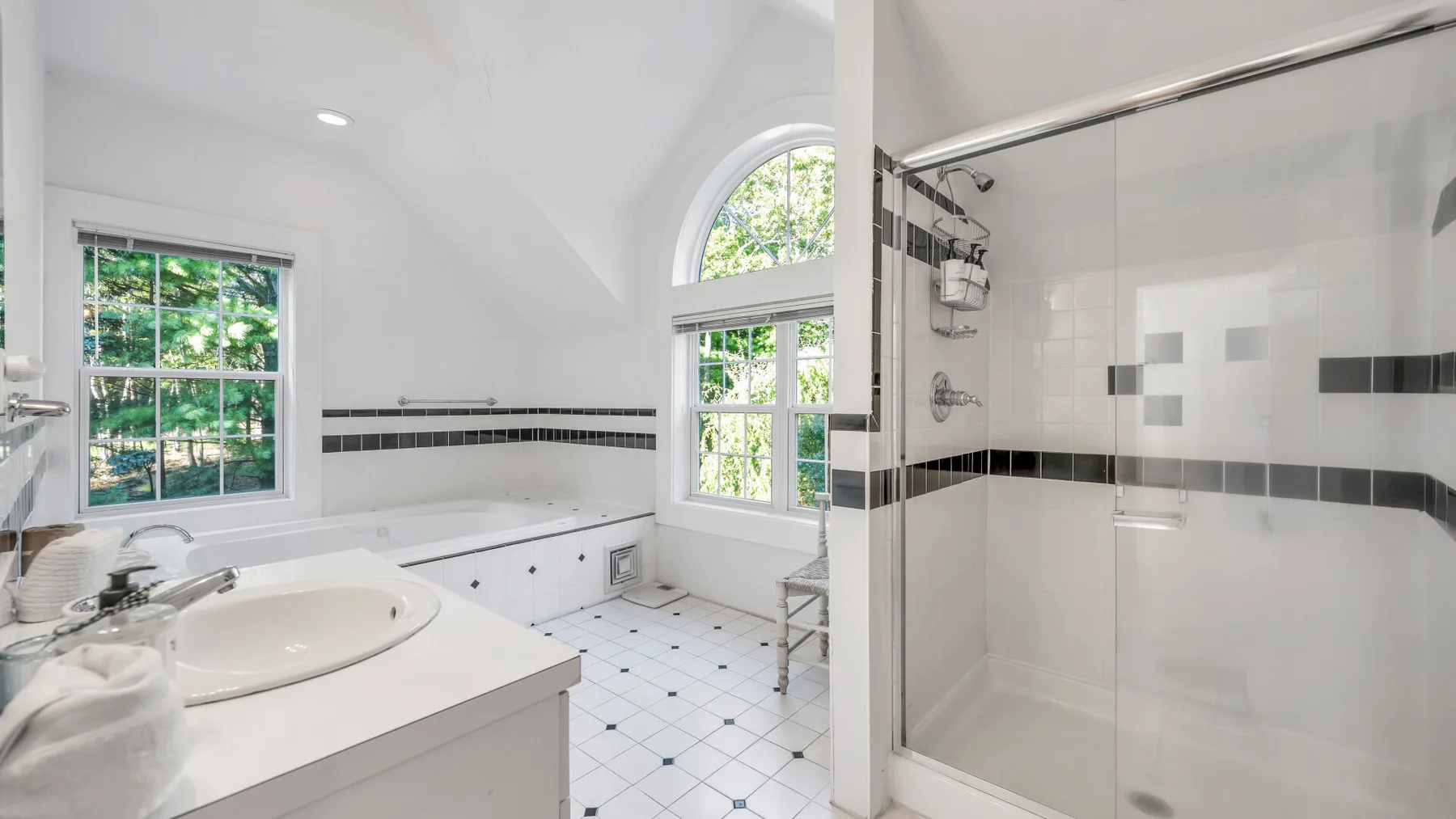 Un baño luminoso con lavabo, ventanas grandes y una ducha de vidrio.