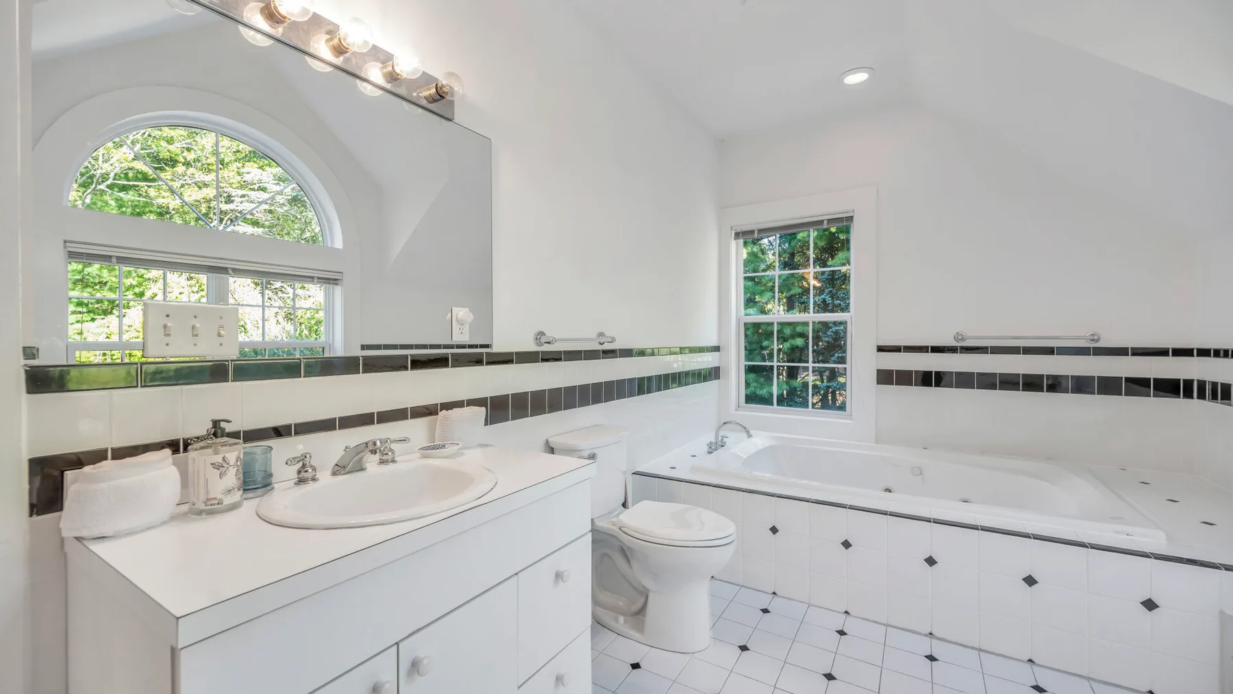 Un baño luminoso con un lavabo largo, bañera y ventana.