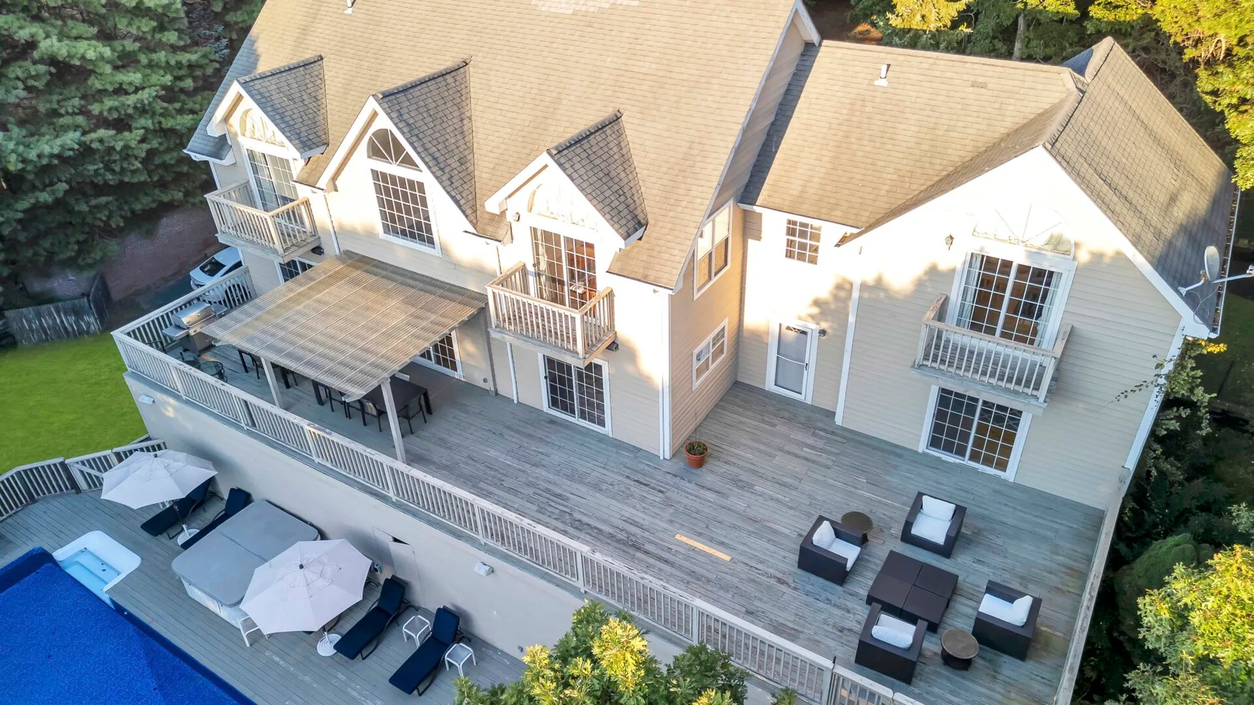 Una casa grande con una amplia terraza junto a una piscina.