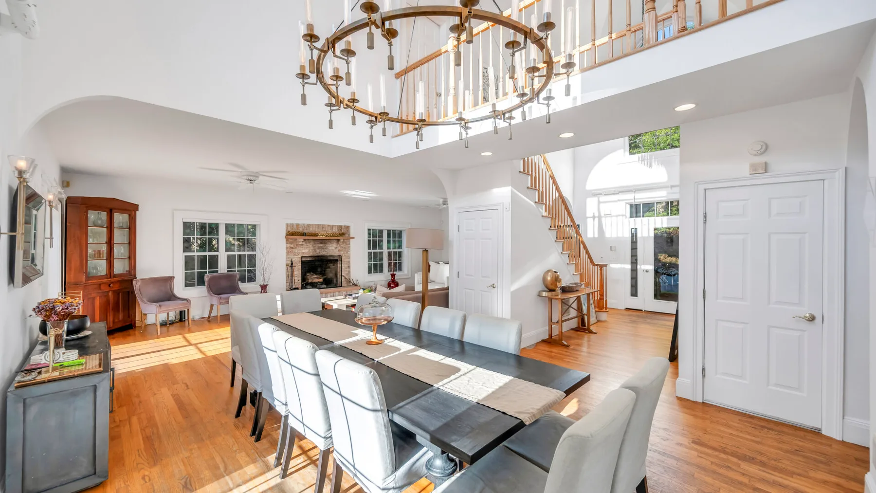 Un luminoso espacio abierto de comedor y sala cuenta con una mesa larga y una escalera.