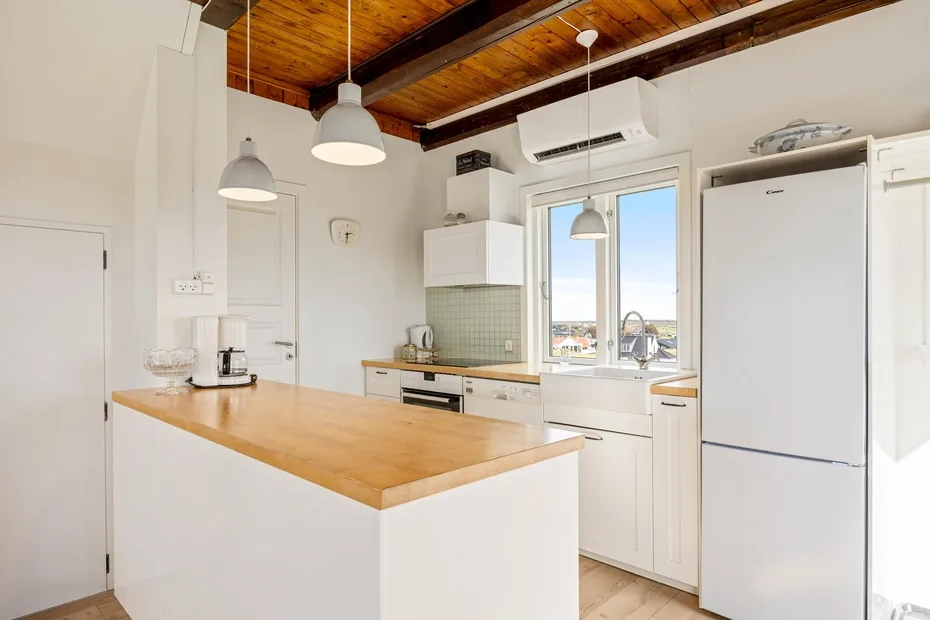 Una cocina luminosa con una isla de madera, armarios blancos y una ventana grande.