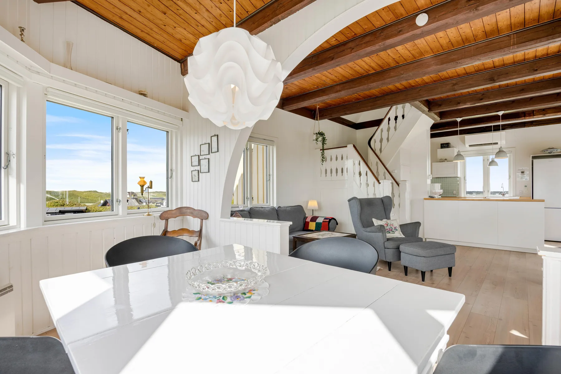 Un luminoso espacio abierto con sala, comedor, cocina y grandes ventanas.