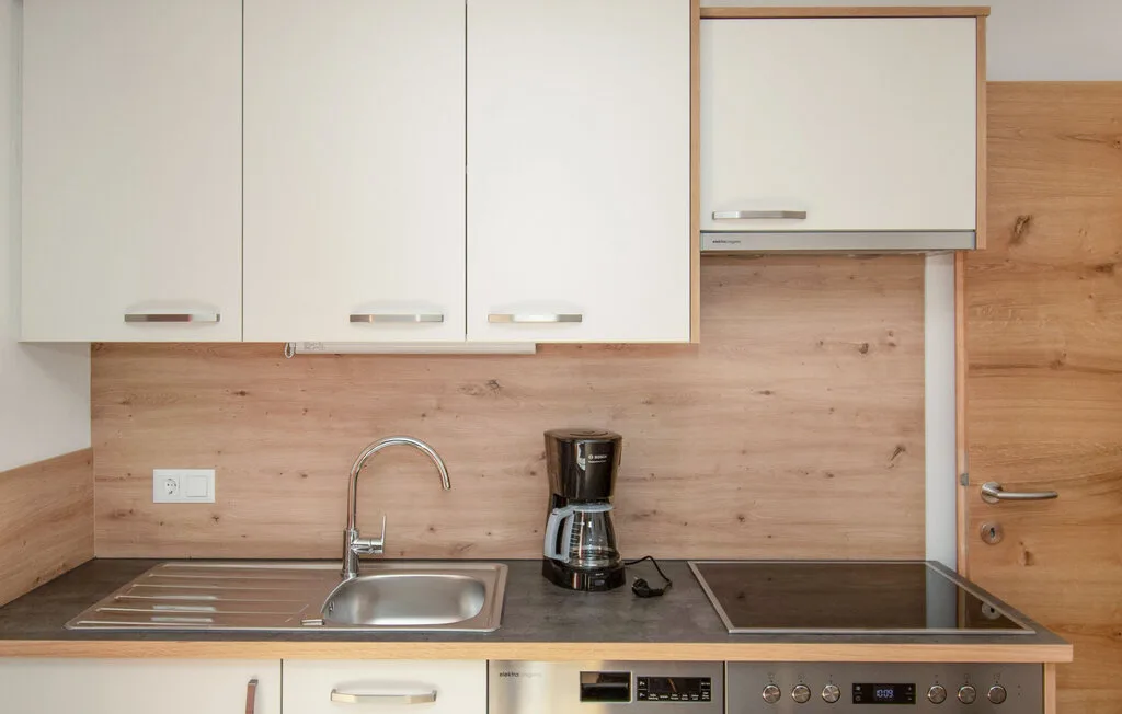 Una cocina compacta con fregadero, cafetera y placa de cocción en la encimera.
