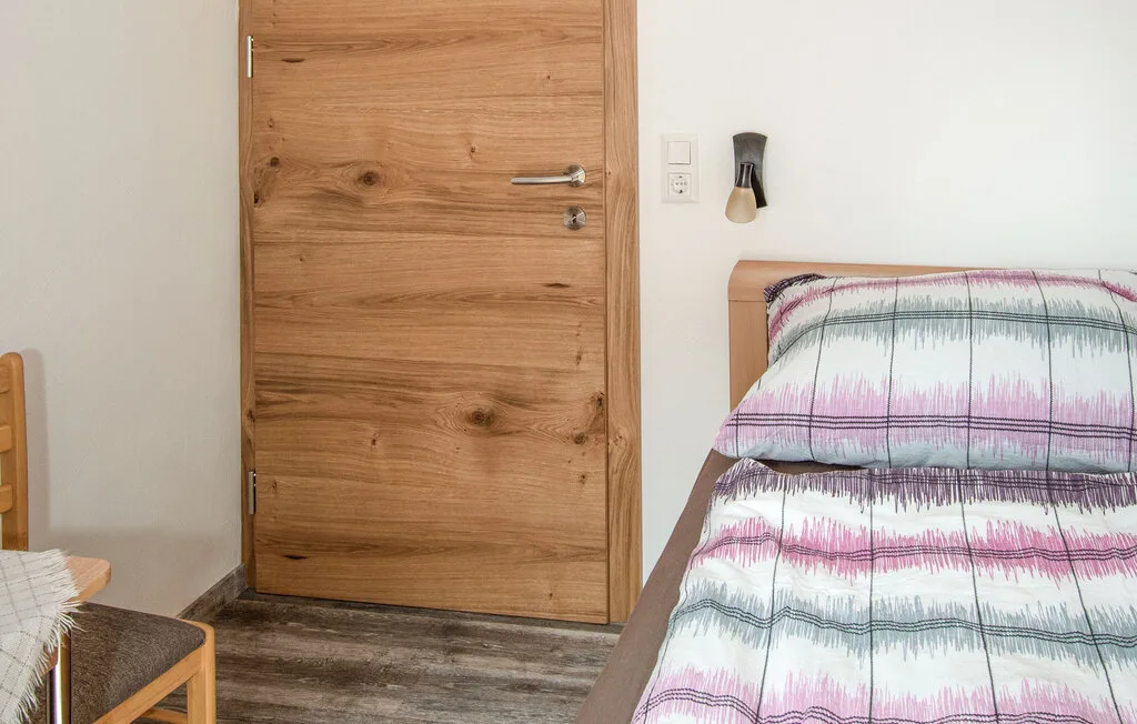 Un dormitorio con una cama cubierta con ropa de cama a rayas junto a una puerta de madera.