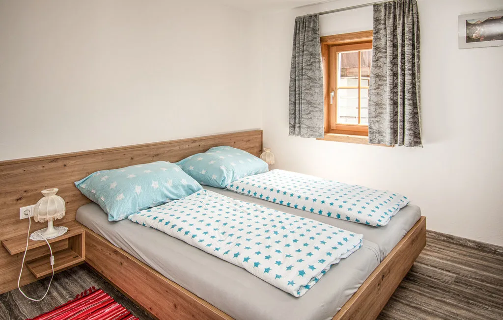 Un dormitorio con una cama de madera vestida con ropa de cama blanca y verde azulado.