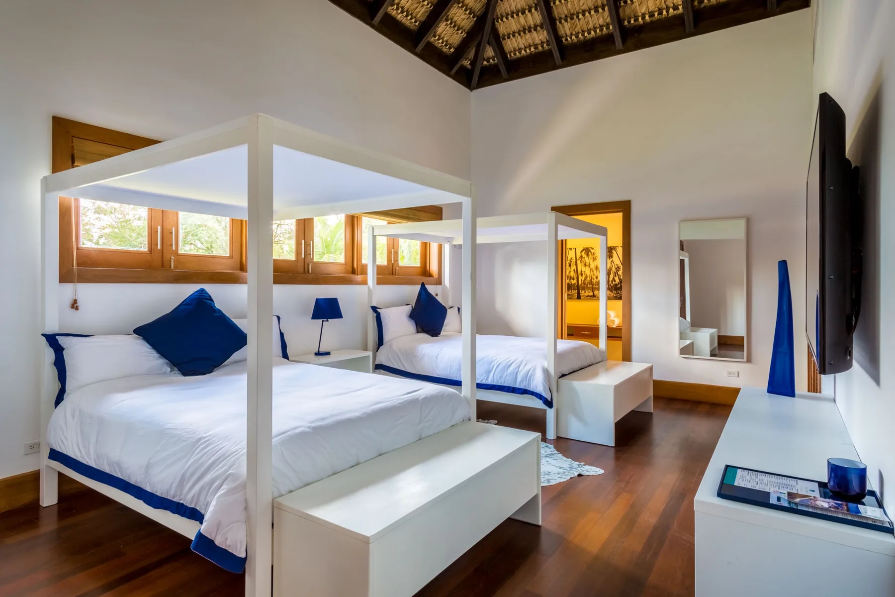 Un dormitorio luminoso con camas con dosel blancas y detalles azules.
