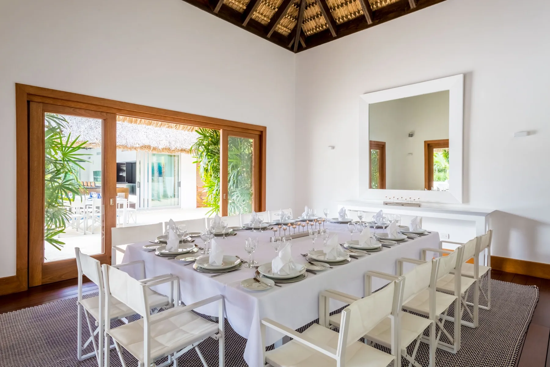 Un comedor con una mesa larga preparada con platos y sillas.
