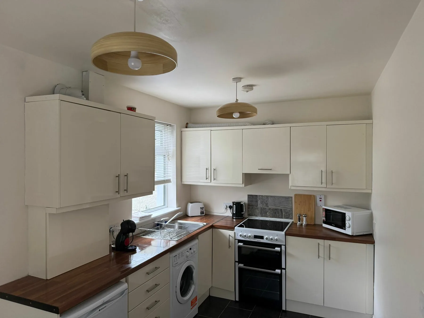 A bright kitchen with white cabinets, dark countertops, and appliances.