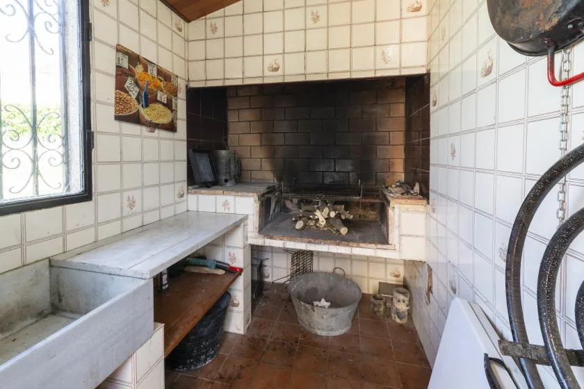 A tiled indoor barbecue area with a built-in grill and countertop.